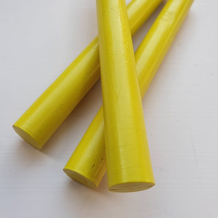 Close-up of three yellow sealing wax sticks, 11mm x 100mm, ideal for crafts, envelopes, and invitations. Smooth handmade finish.