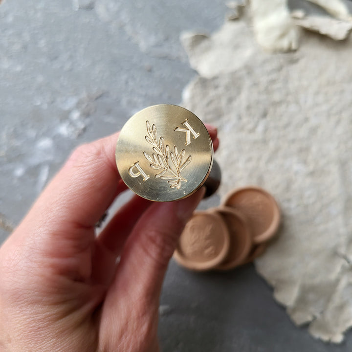 Brass stamp with 'Willow' monogram design for initials 'K' and 'P,' shown alongside peach wax seals for personalized stationery.