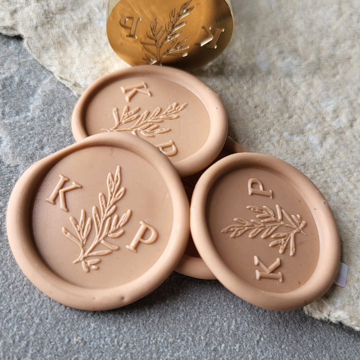 Set of peach 'Willow' monogram wax seals with initials 'K' and 'P,' highlighting the intricate botanical design and adhesive backing.