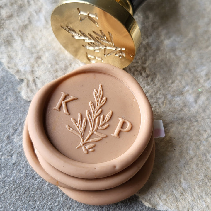 Detailed view of peach 'Willow' monogram wax seals with initials 'K' and 'P,' made with hand-mixed wax and adhesive backing.