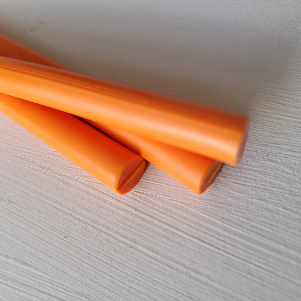 Angled view of 7mm tangerine sealing wax sticks, designed for glue gun use at 75-85°C. Perfect for crafts and UK-made.