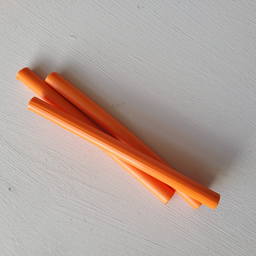 Top-down view of 7mm tangerine sealing wax sticks, suitable for creating wax seals with a glue gun. Made in Britain.