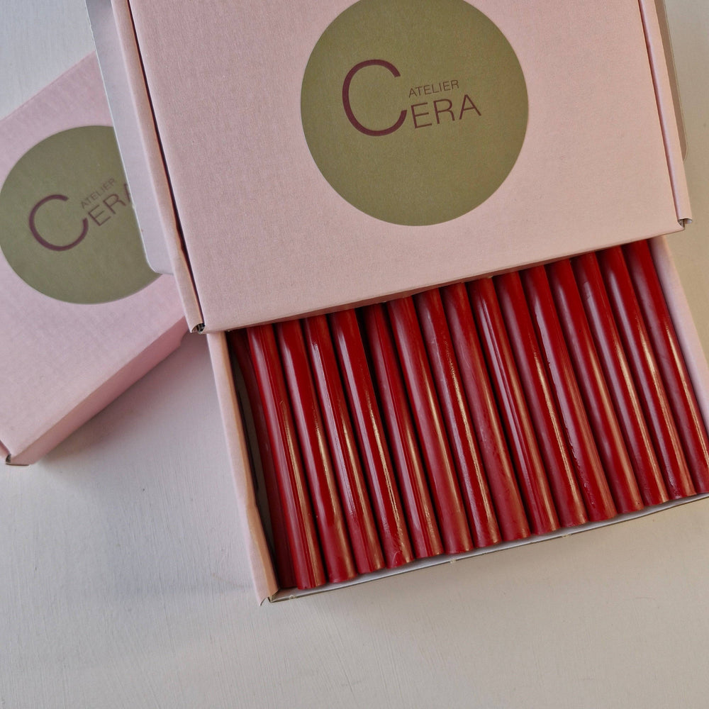 Open box of 30 red wax sticks, neatly arranged, with Atelier Cera branding on the pink packaging.