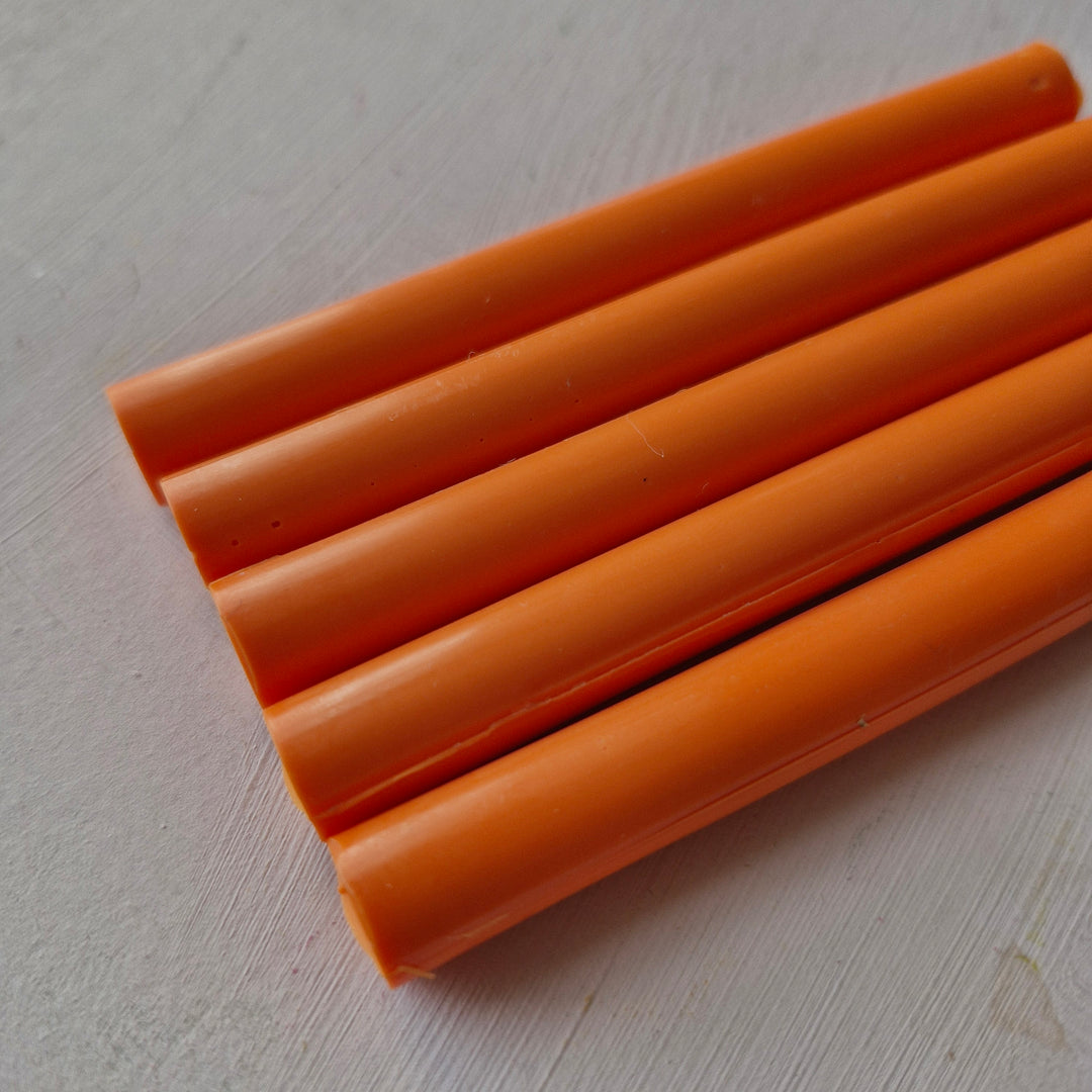 Close-up of 11mm tangerine-colored cylindrical office supplies, part of a box of 50 for versatile office use.