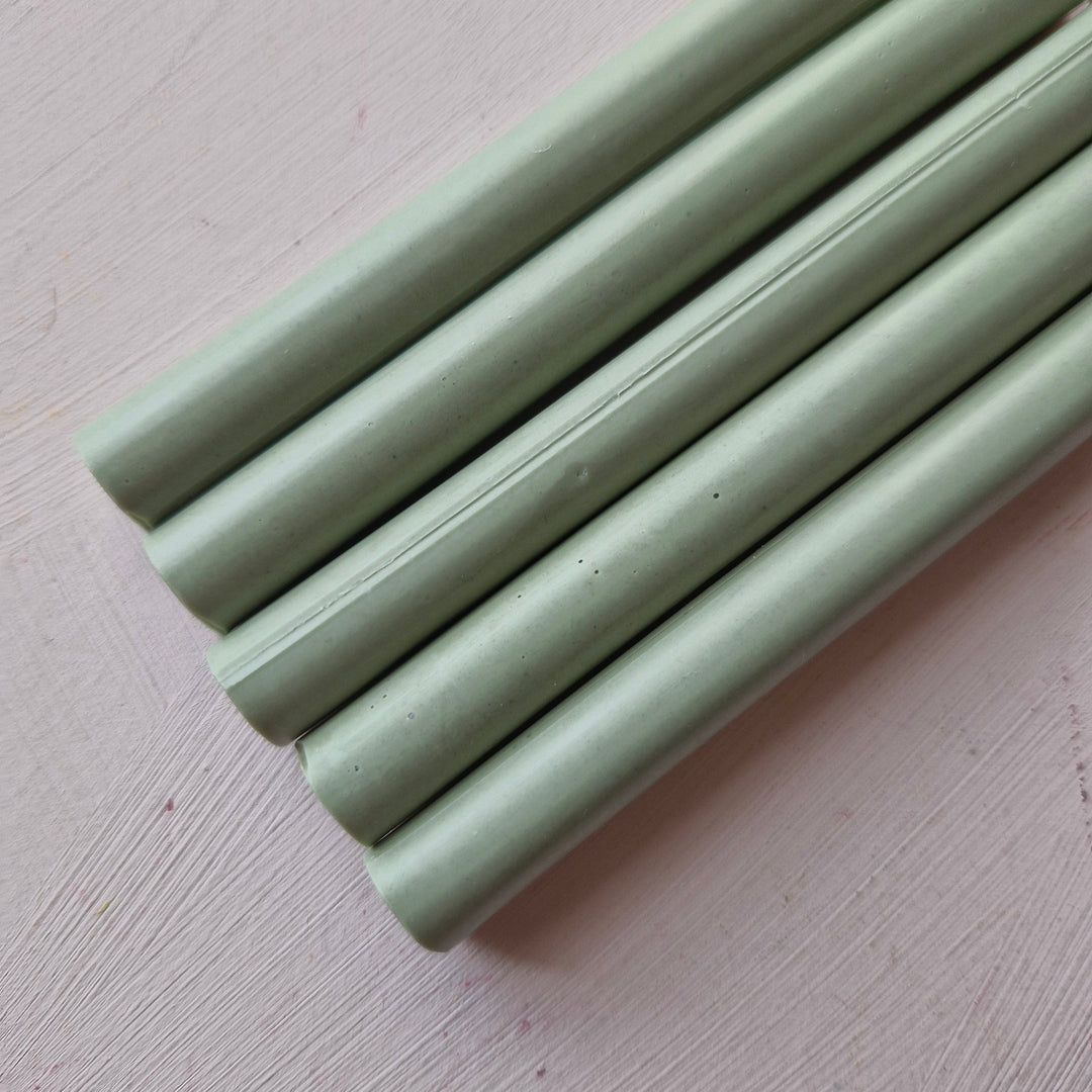 Close-up of sage green 11mm x 100mm handmade sealing wax sticks from a box of 50. Ideal for crafts and sealing tasks.