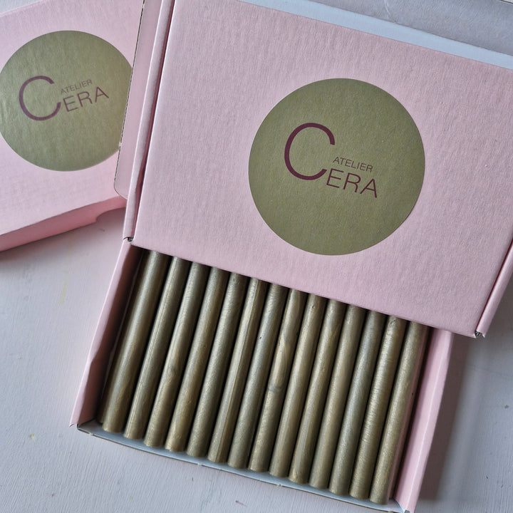 Close-up of a pink box labeled 'Atelier Cera' showcasing 30 11mm French gold sticks for office and crafting purposes.