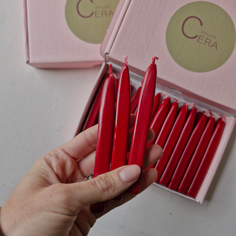 Hand holding red sealing wick wax sticks from a box of 26, showcasing their size and vibrant color.