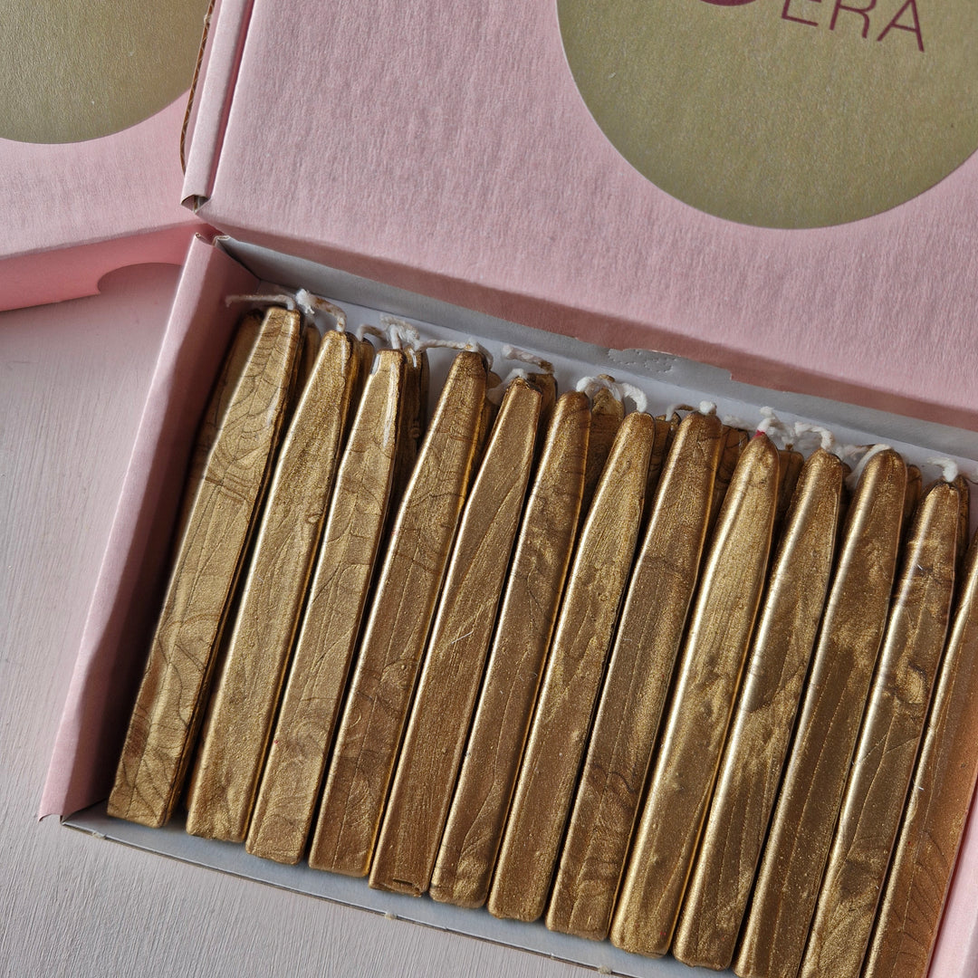 Box of 26 gold sealing wick wax sticks displayed in a pink box with a branded Atelier Cera label, ideal for crafts and sealing projects.