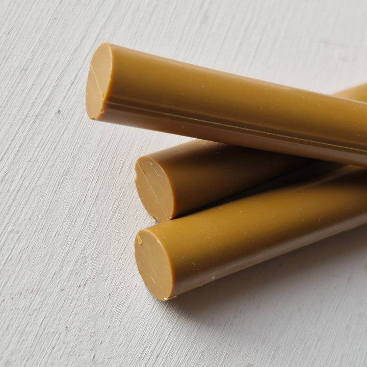 Close-up of three toffee-colored 11mm sealing wax sticks on a white surface, ideal for handmade crafts and invitations.