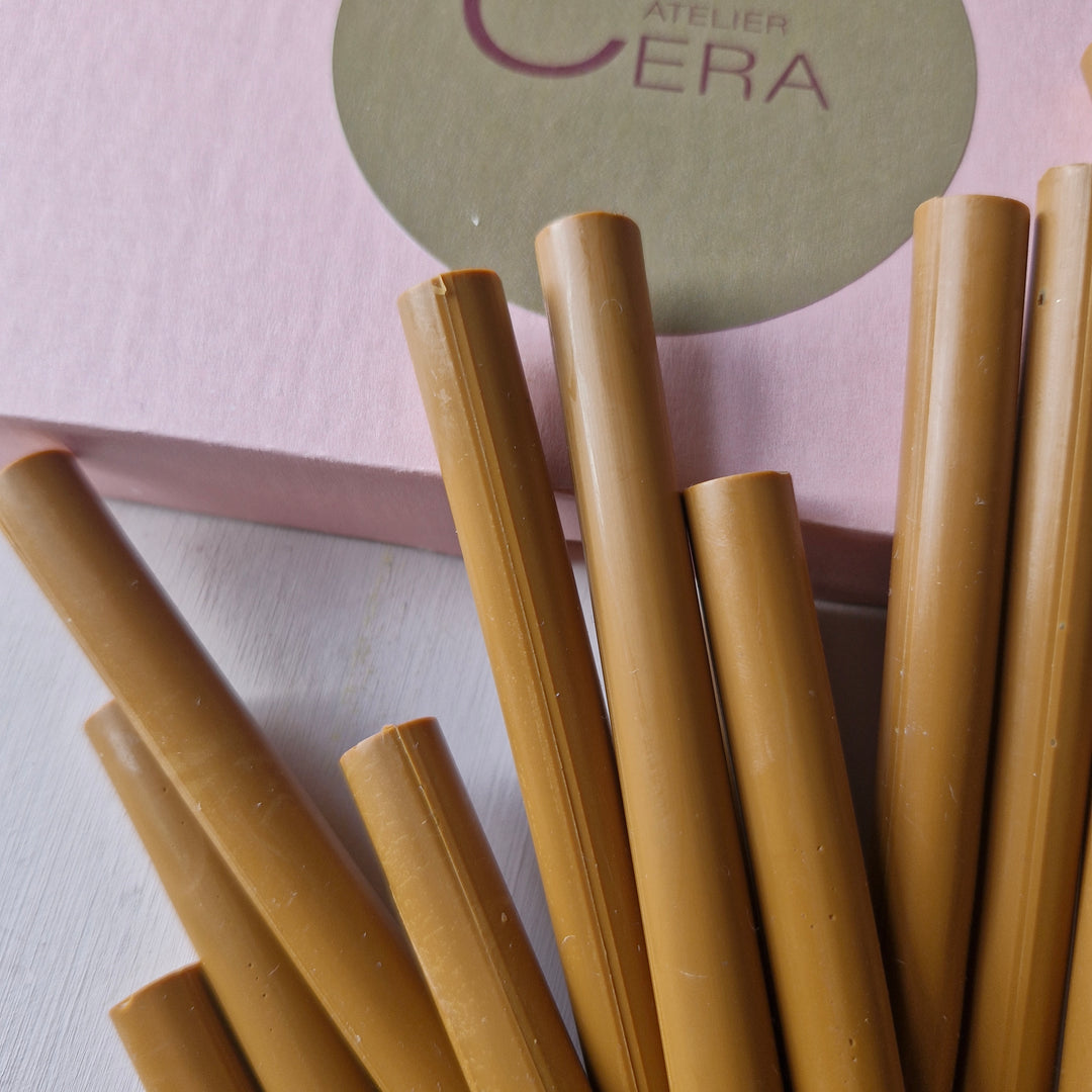 Close-up view of toffee-colored 11mm sealing wax sticks with a pink Atelier Cera branded box in the background.