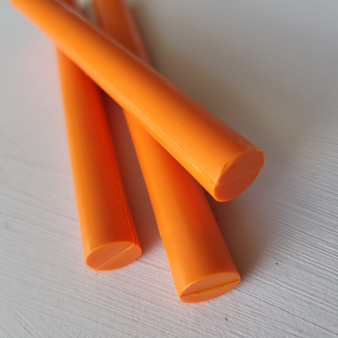 Close-up of three tangerine-colored 11mm sealing wax sticks from a 10-pack, ideal for crafting and office use.