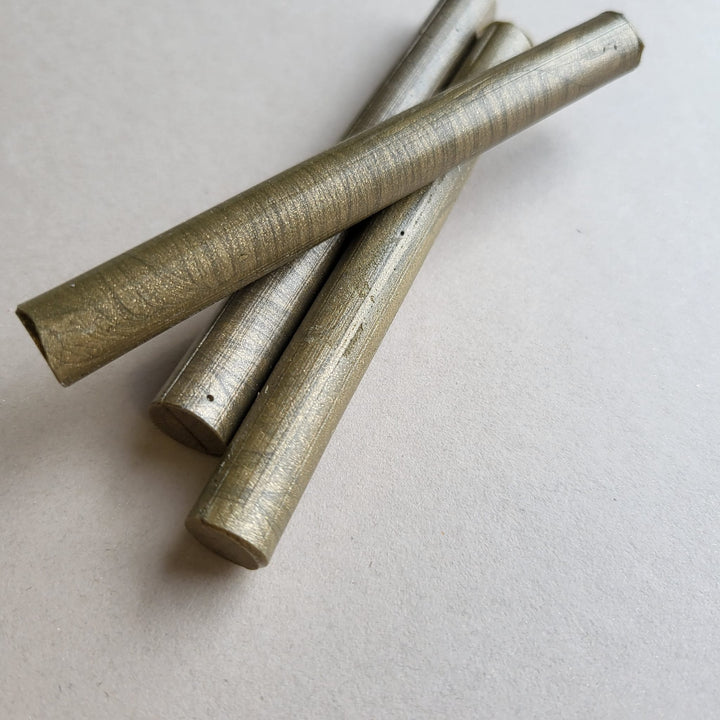 Close-up of three French Gold 11mm sealing wax sticks with a metallic finish, ideal for invitations and gifts. Durable and handmade quality.