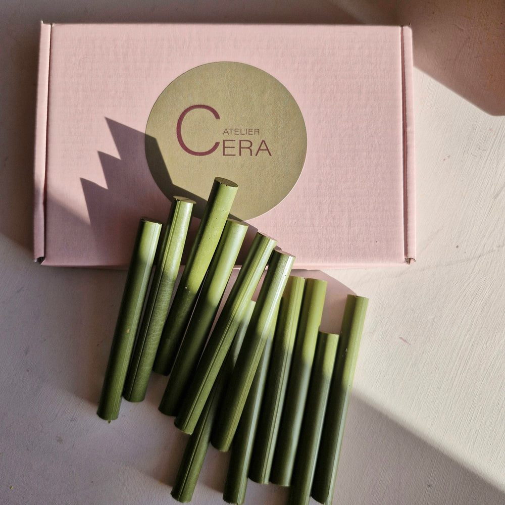 Olive green 11mm sealing wax sticks displayed in front of a pink Atelier Cera box. Perfect for high-quality sealing needs.