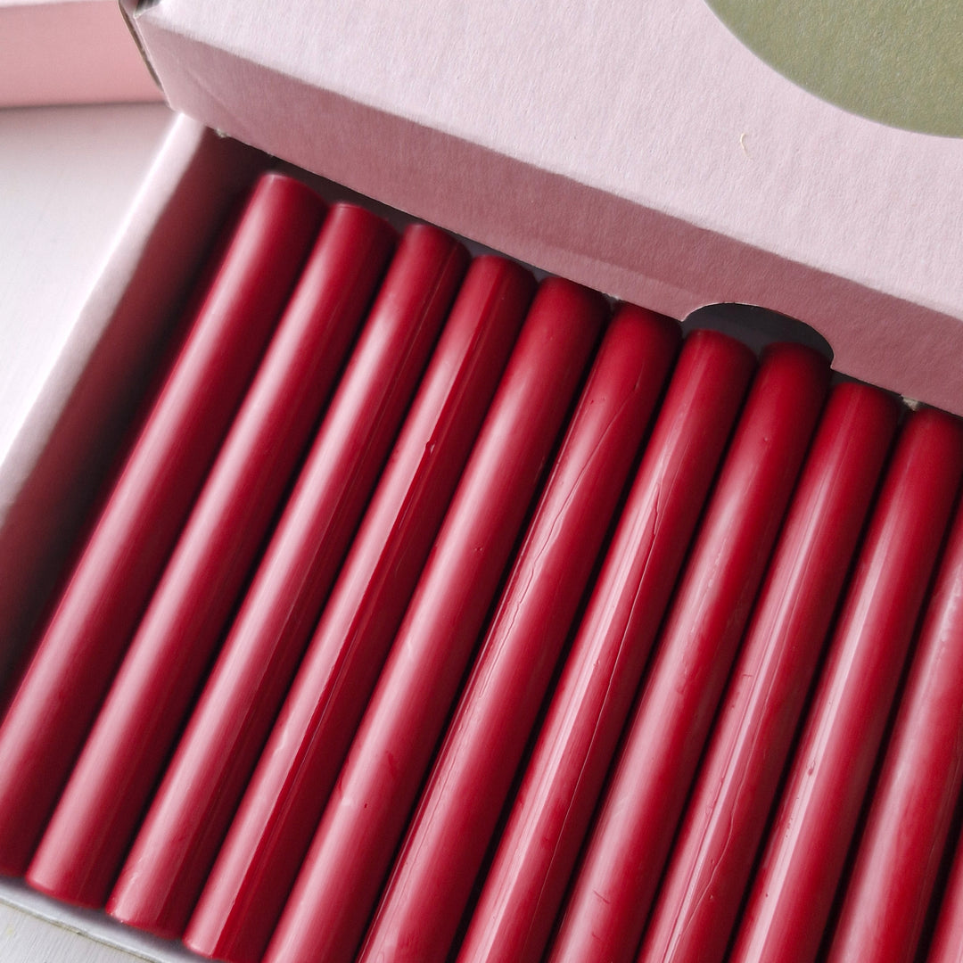 Close-up of red wax sticks in a box, showcasing their smooth texture and vibrant color for sealing tasks.