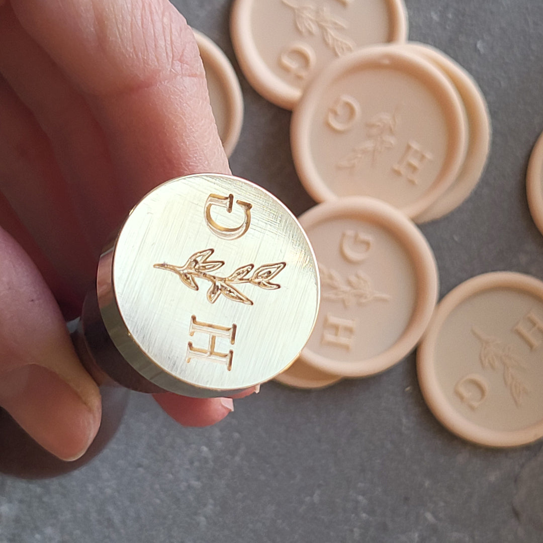 Close-up of a brass stamp head with 'Meadow' monogram design, paired with matching wax seals for stationery.