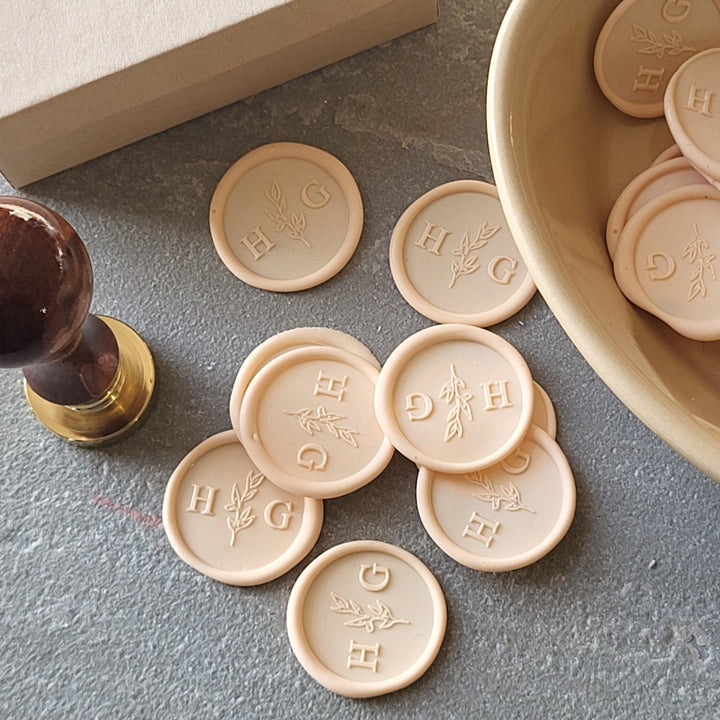 Set of 'Meadow' monogram wax seals with adhesive backing, displayed with a wooden stamp handle for customization.