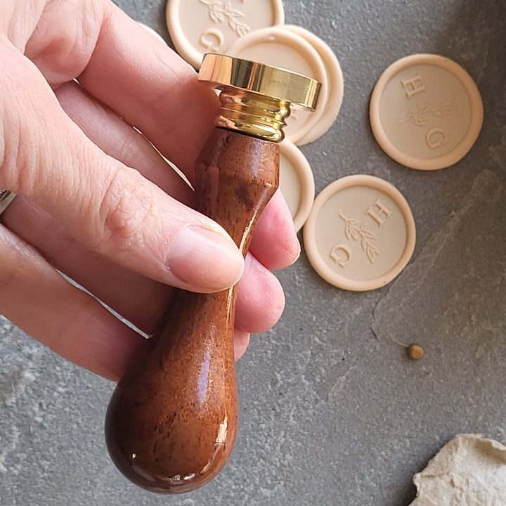 Wooden handle and brass stamp for creating 'Meadow' monogram wax seals, paired with adhesive wax seals.