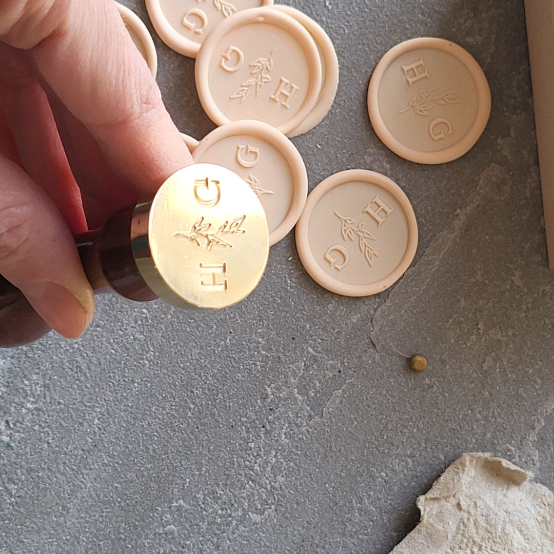 Detailed view of a brass stamp for 'Meadow' monogram wax seals, showcasing initials and leaf design.