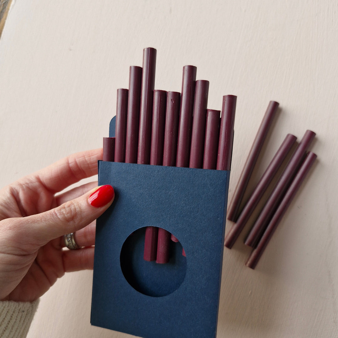 Pack of 10 burgundy 7mm sealing wax sticks in a navy blue box, ideal for creating up to 50 seals. Perfect for envelopes, invitations, and crafts.