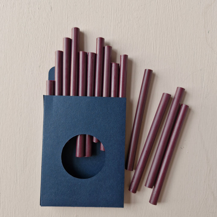 Pack of 10 burgundy 7mm sealing wax sticks in a navy blue box. Ideal for creating up to 50 wax seals on envelopes and invitations. Compatible with cool melt glue guns.