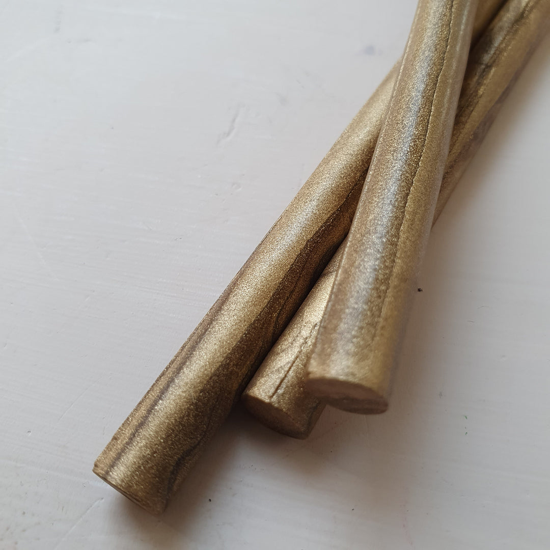 Angled view of 7mm gold wax sealing sticks with a smooth metallic texture. Designed for glue gun use, making 4-5 seals each.