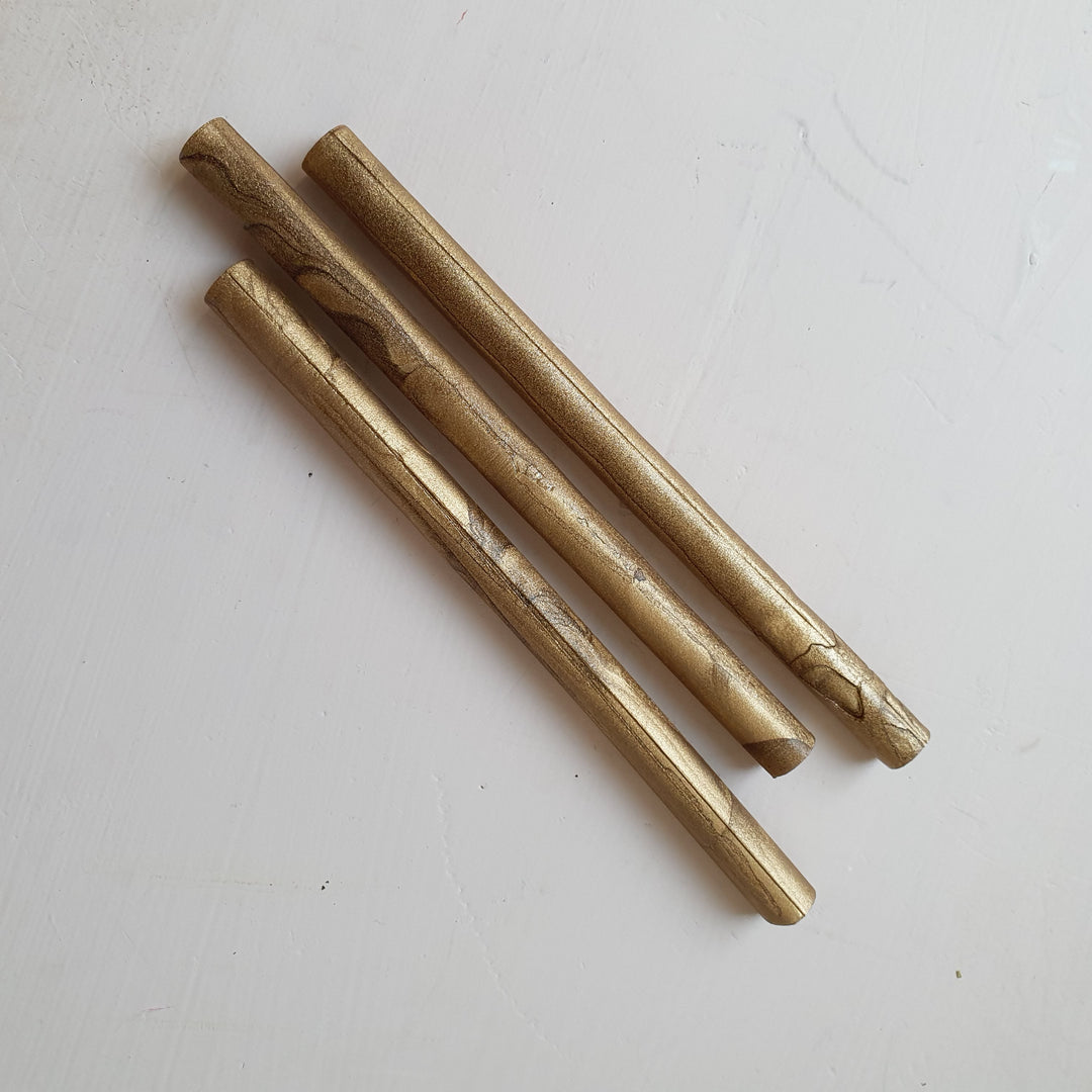 Three 7mm gold wax sealing sticks with a metallic sheen, displayed on a white surface. Perfect for glue gun sealing projects.