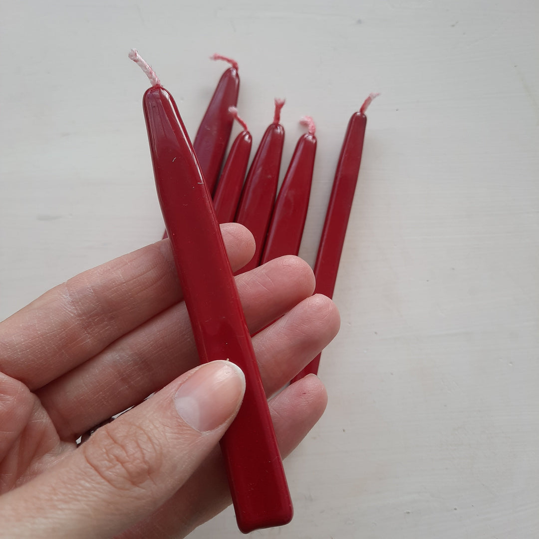 Hand holding a red sealing wick wax stick with a pink wick, ideal for traditional wax seals. British handmade and easy to use.