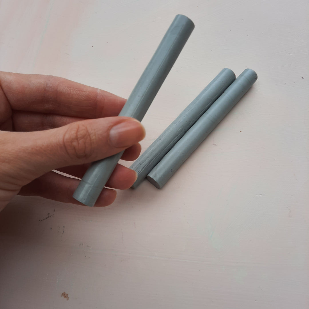 Hand holding an 11mm mid grey sealing wax stick, showcasing its size and flexibility for DIY seal-making with a hotmelt glue gun.