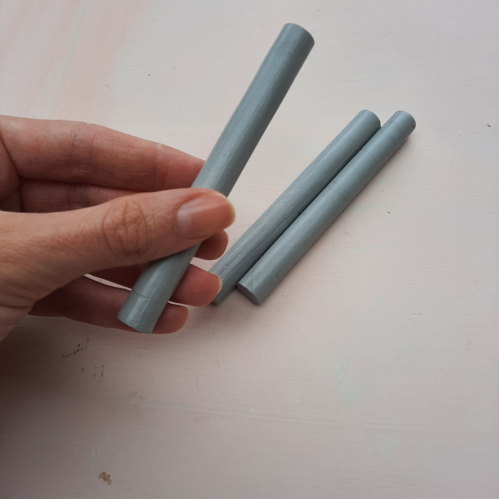 Hand holding an 11mm mid grey sealing wax stick, showcasing its size and flexibility for DIY seal-making with a hotmelt glue gun.